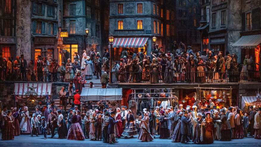 A large group of people mill about on an 18th century city street.