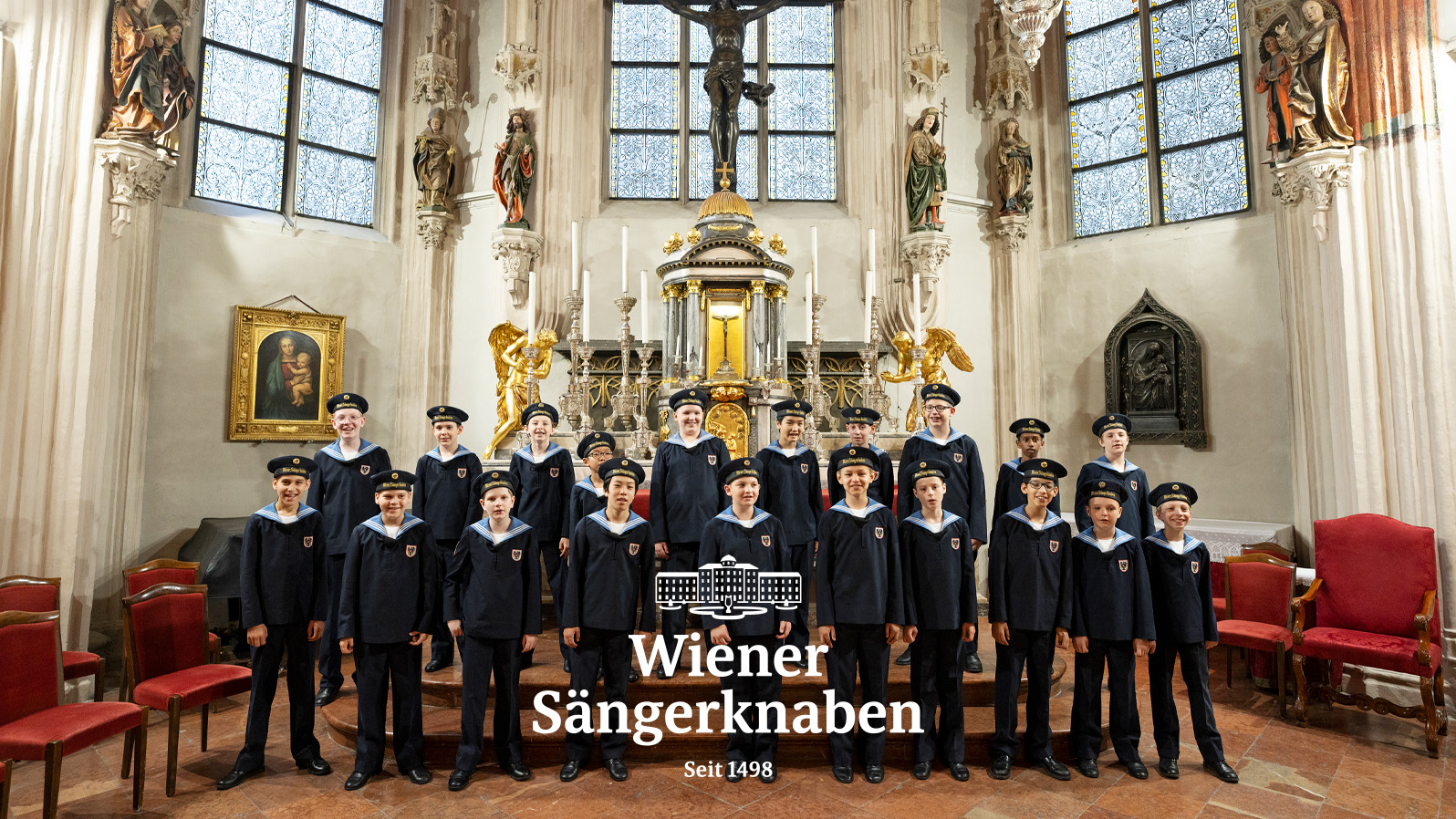 A group of boys in sailor outfits smile in a church. Text reads,