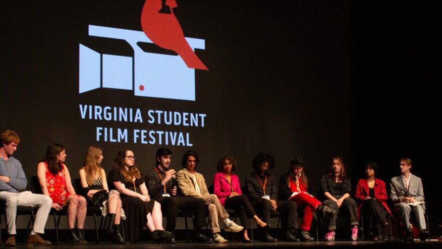 A group of young filmmakers it on a stage. On the screen behind them, a red bird sits on top of a movie camera. Text reads,