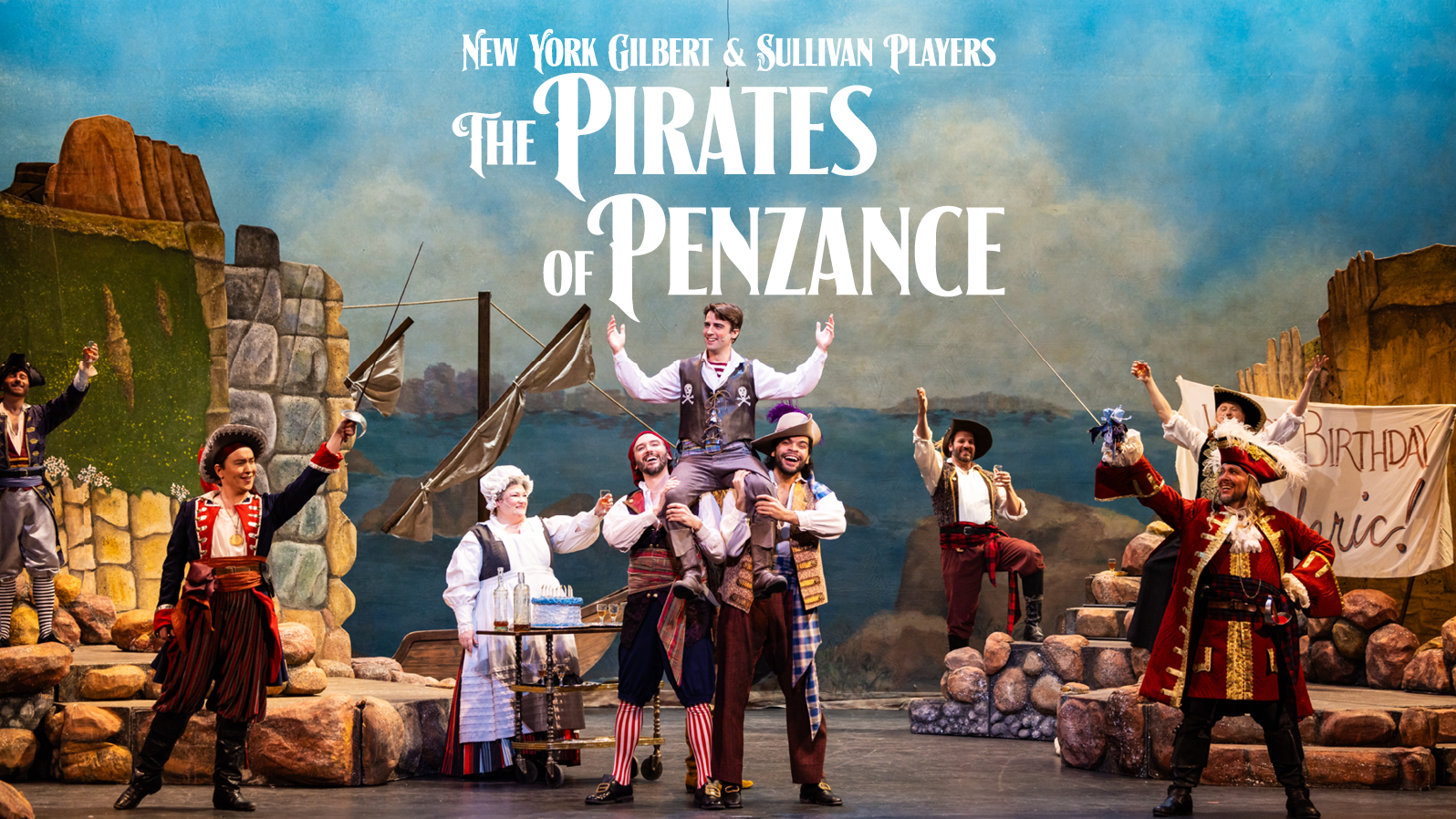 Pirates raise a man up on stage while people around them cheer. Text reads, 